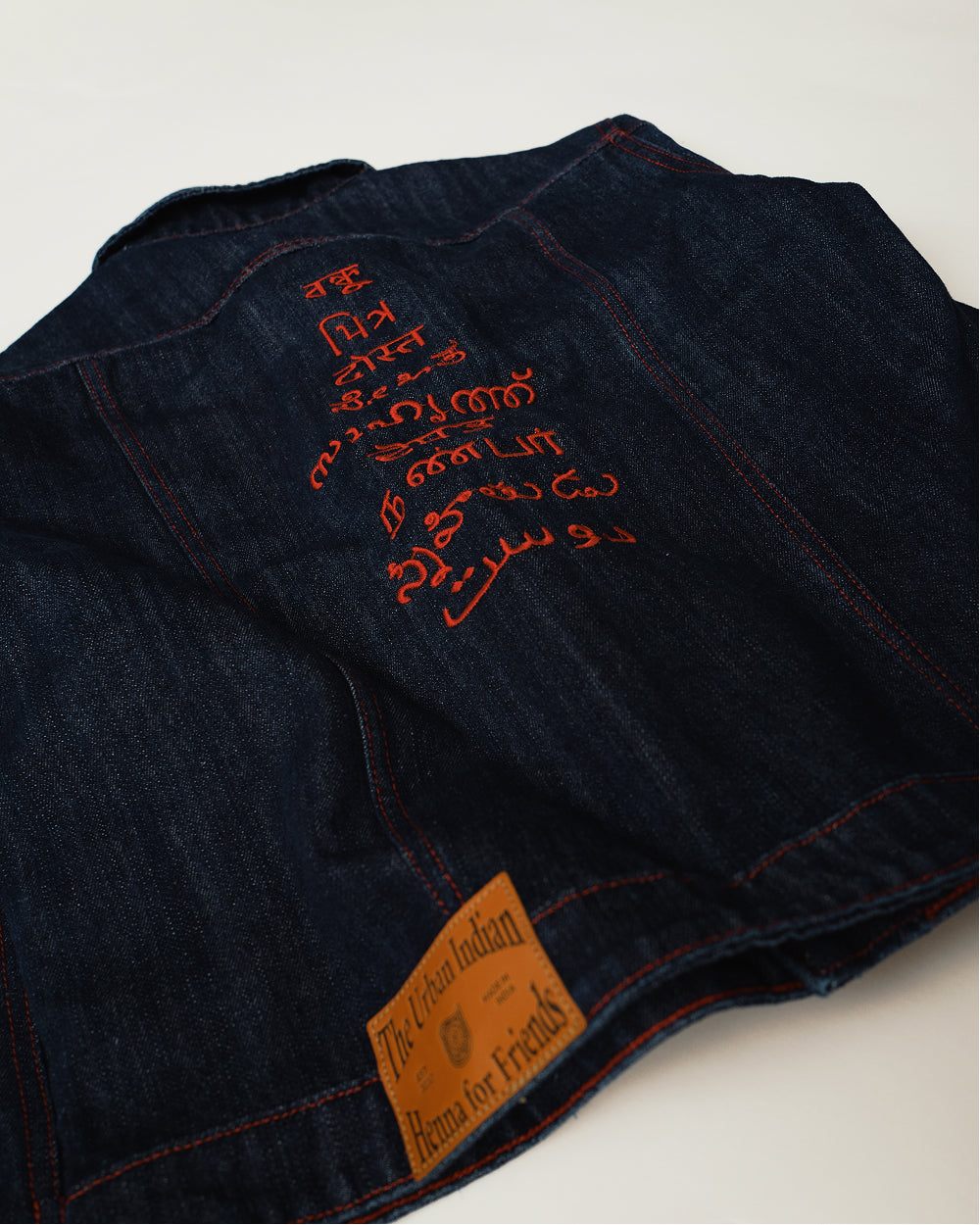 Close angle on the Raw Indigo Khadi denim jacket, handloom weave and rust stitching with the Henna for Friends leather patch