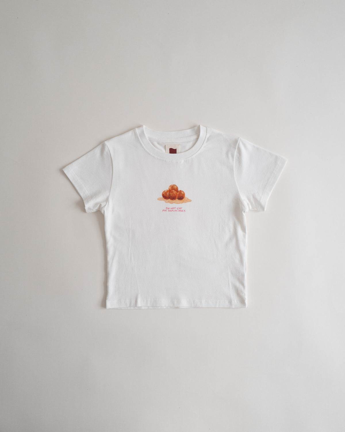Sweets Baby Tee in Gulab Jamun, flat lay, white with a small watercolor gulab jamun on the chest #Color_Gulab Jamun