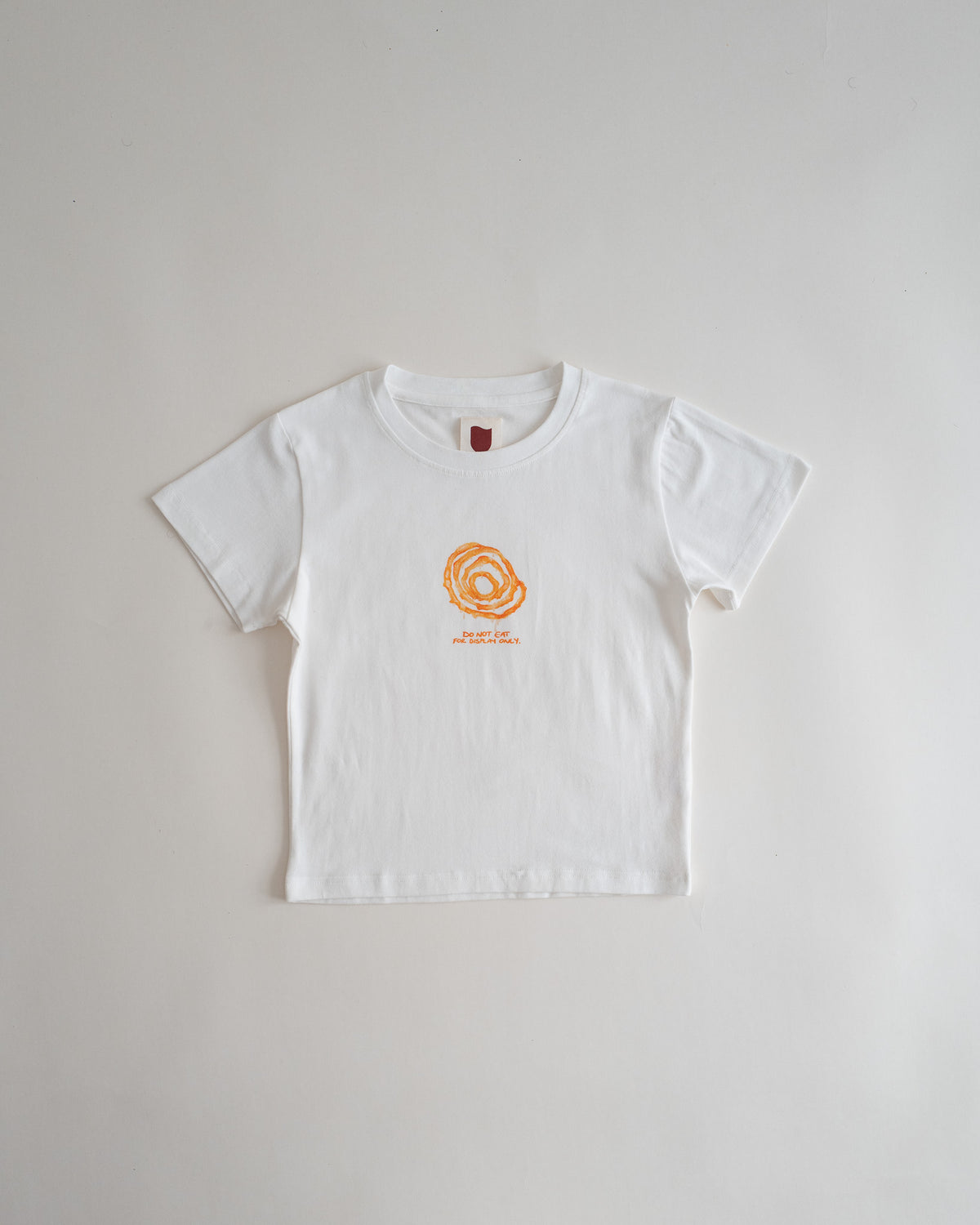Sweets Baby Tee in Jalebi, flat lay, white with a small watercolor jalebi on the chest #Color_Jalebi