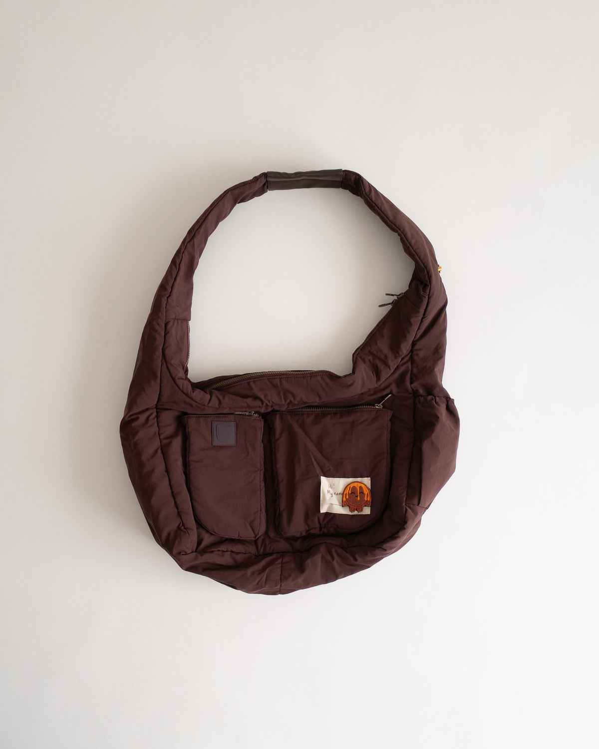 Gulab Bag in deep gulab jamun brown, flat lay, puffed body with front pockets and a mood-ring name tag
