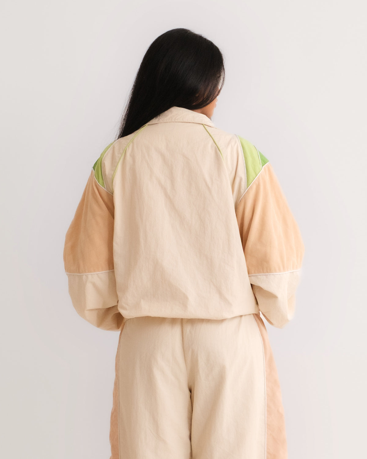 Woman from behind in the Pista Green Sweets Track Jacket and Track Pants, green felt patches on the shoulders #Color_Pista Green