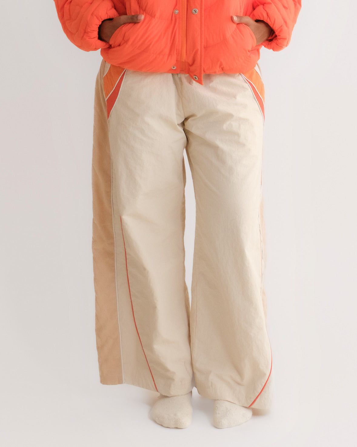 Woman in the Sweets Track Pants in Saffron Orange worn with the Jalebi Down Jacket #Color_Saffron Orange