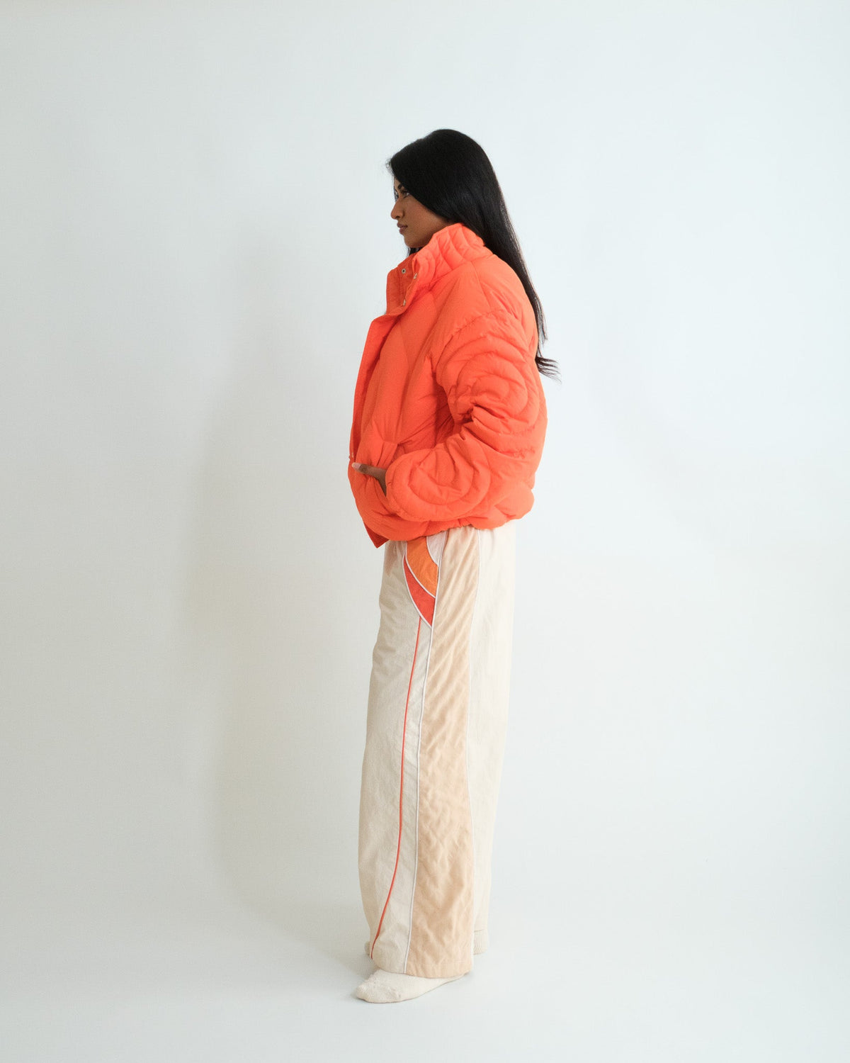 Side view of the Sweets Track Pants in Saffron Orange worn with the Jalebi Down Jacket #Color_Saffron Orange