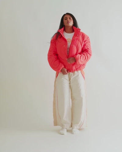 Video of a woman in the Jalebi Down Jacket with the Sweets Track Pants in Saffron Orange