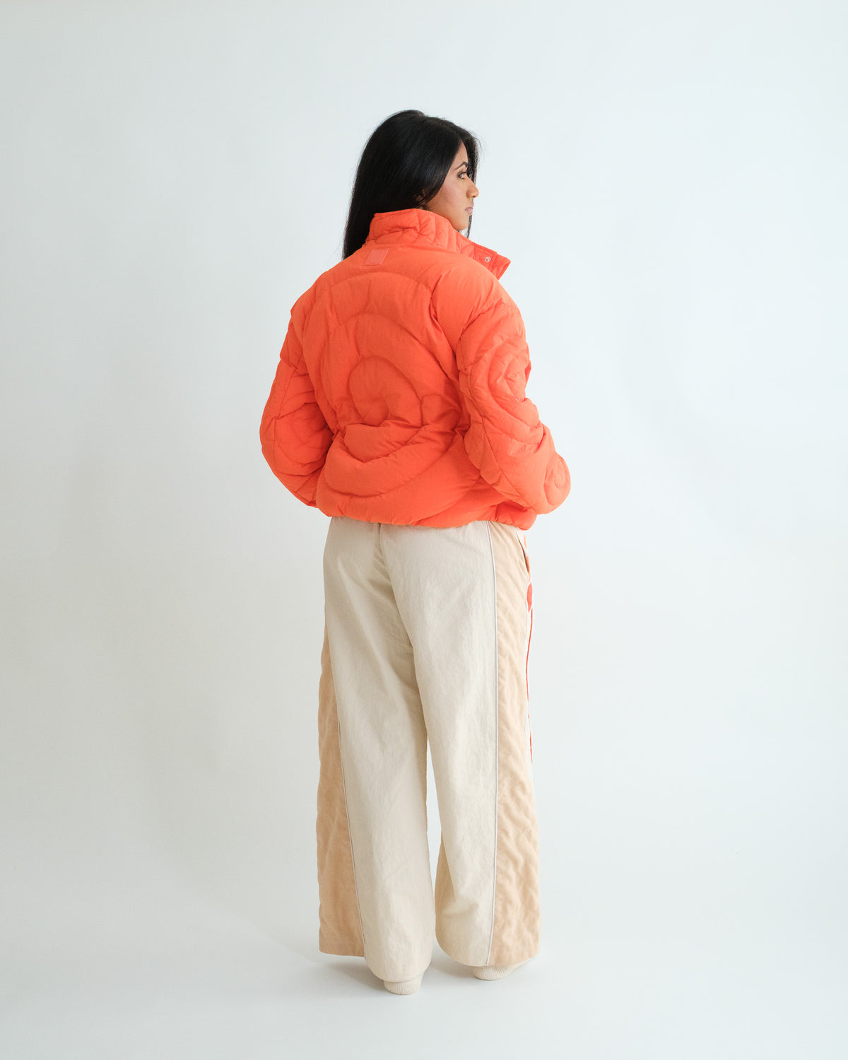 Woman from behind in the Jalebi Down Jacket, spiral jalebi quilting coiling across the back
