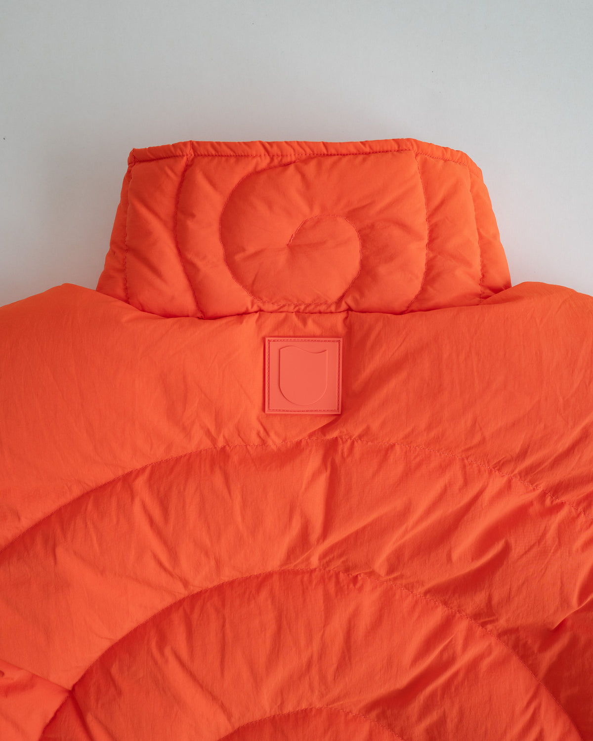 Close-up of the quilted spiral collar and tonal patch on the back of the Jalebi Down Jacket