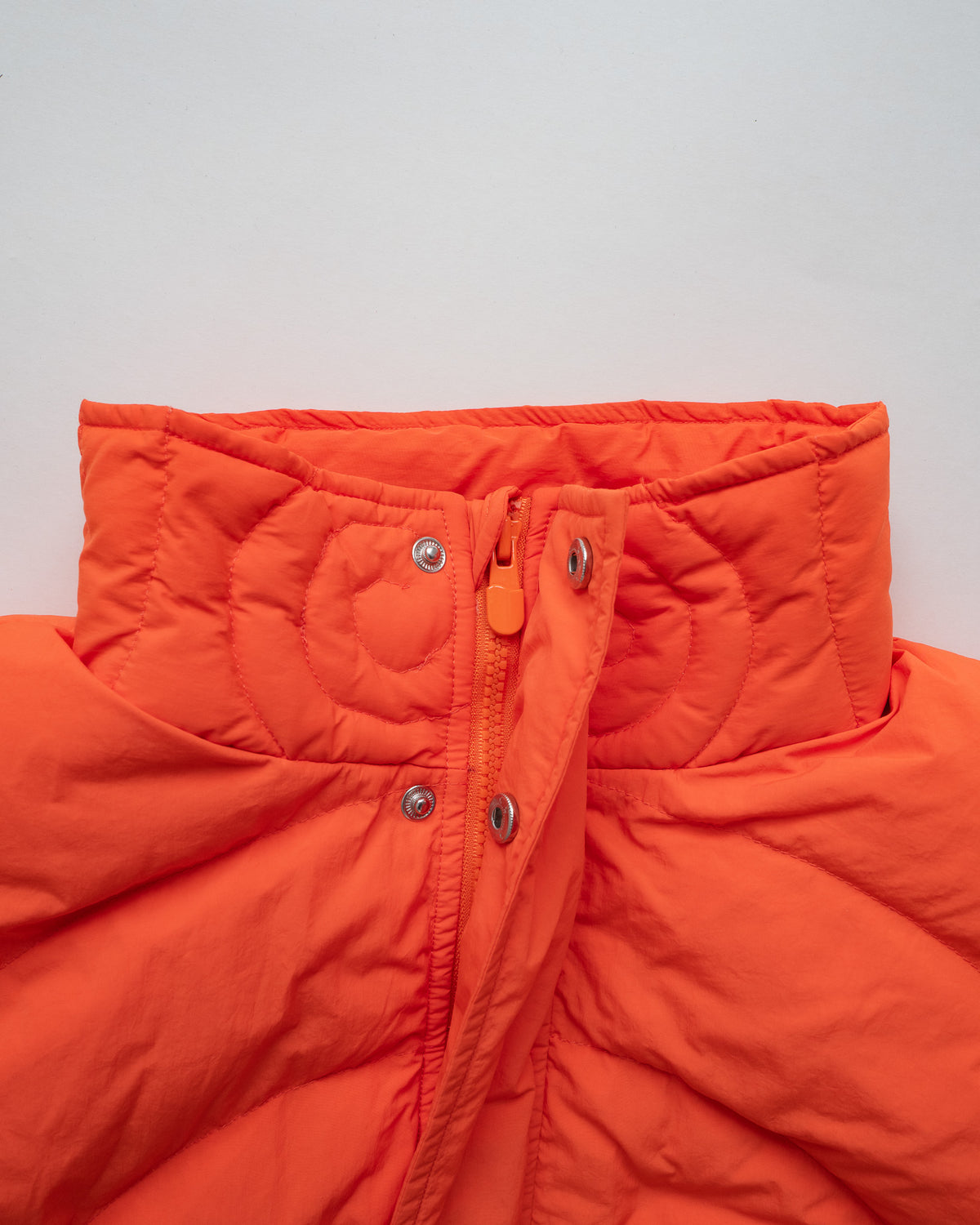 Close-up of the Jalebi Down Jacket collar, snap buttons and zip pull