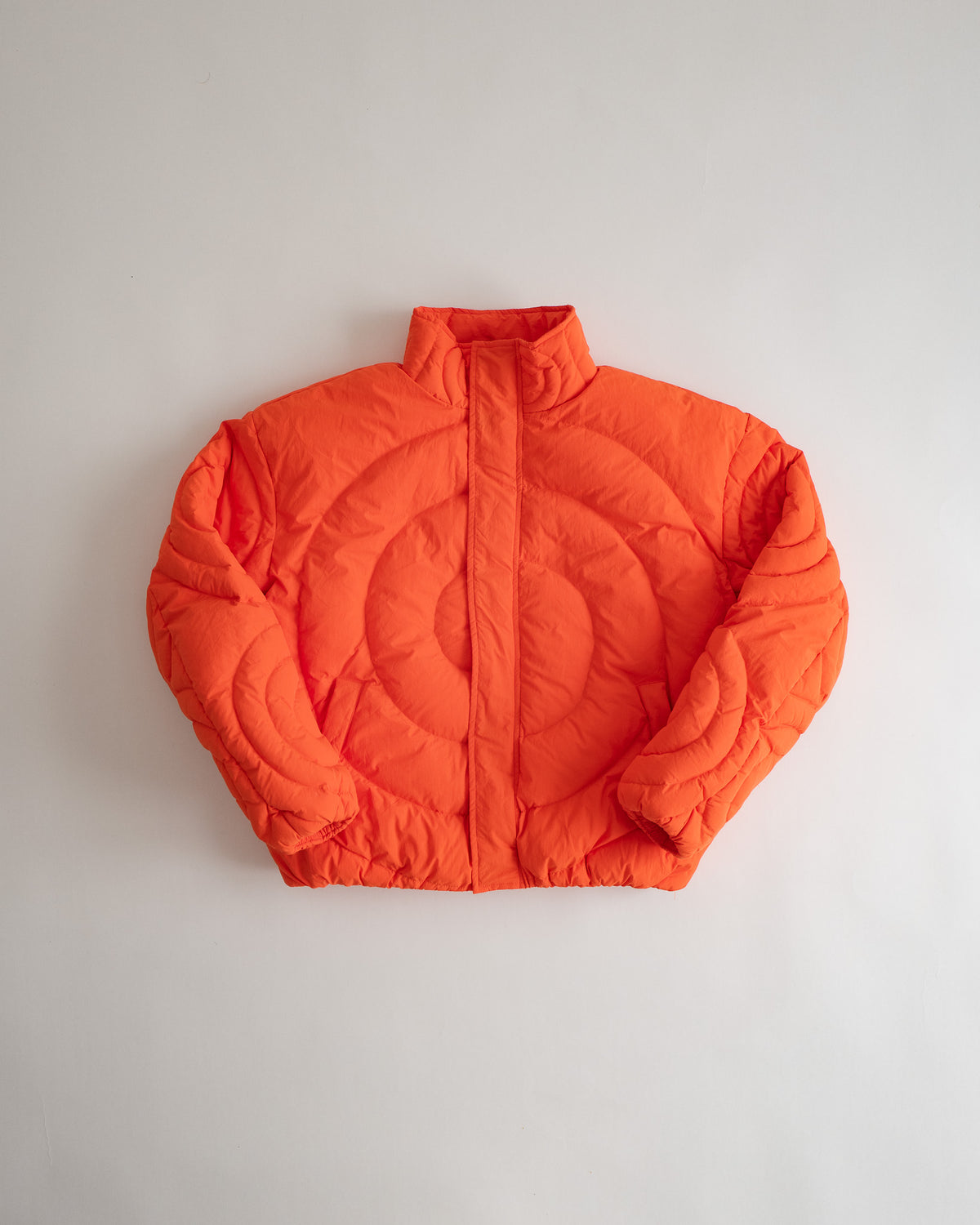 Jalebi Down Jacket, flat lay from the front, spiral jalebi quilting in jalebi orange