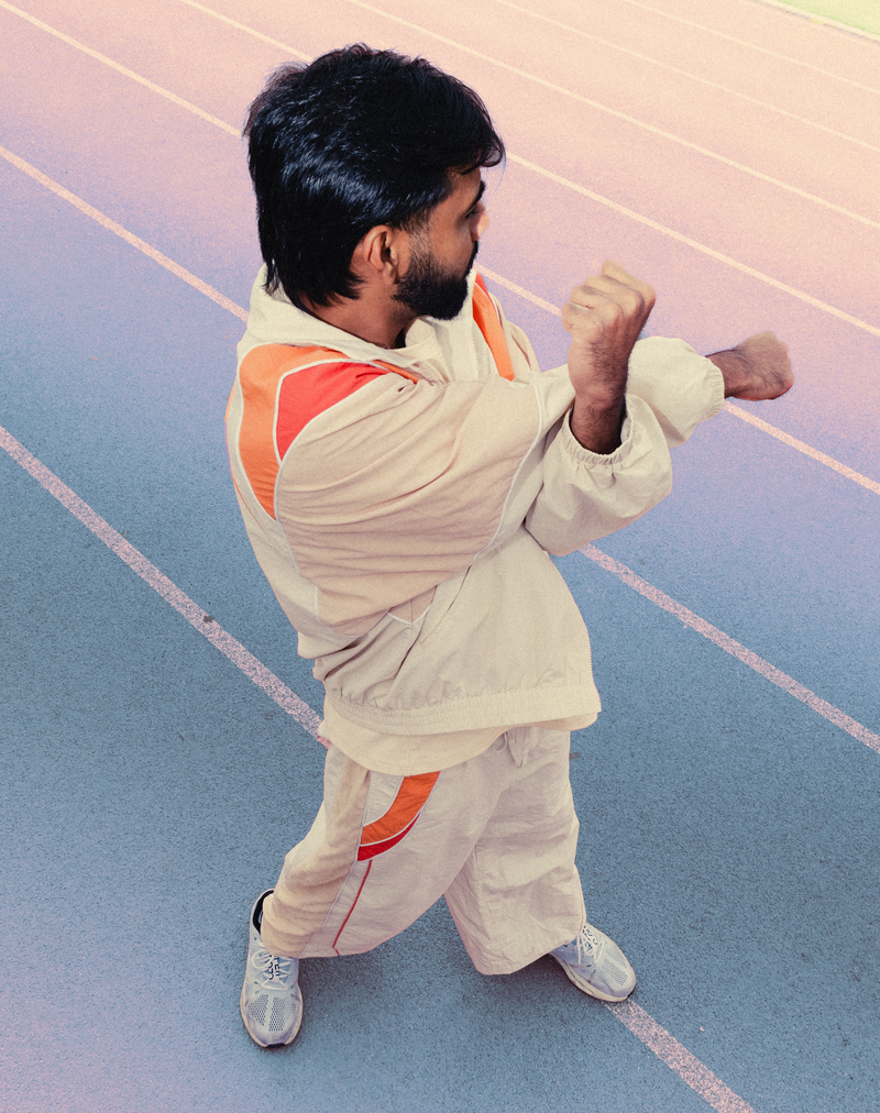 Man throwing a punch on a blue running track in the Saffron Orange Sweets Track Set