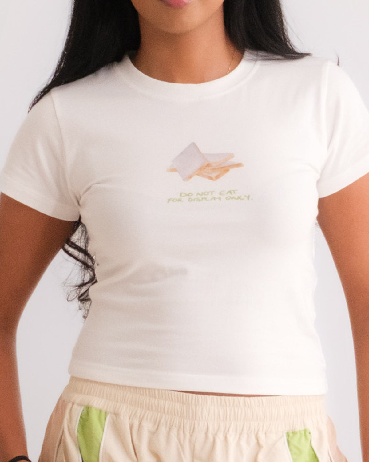 Woman wearing the Sweets Baby Tee in Kaju Katli with the Sweets Track Pants in Pista Green #Color_Kaju Katli
