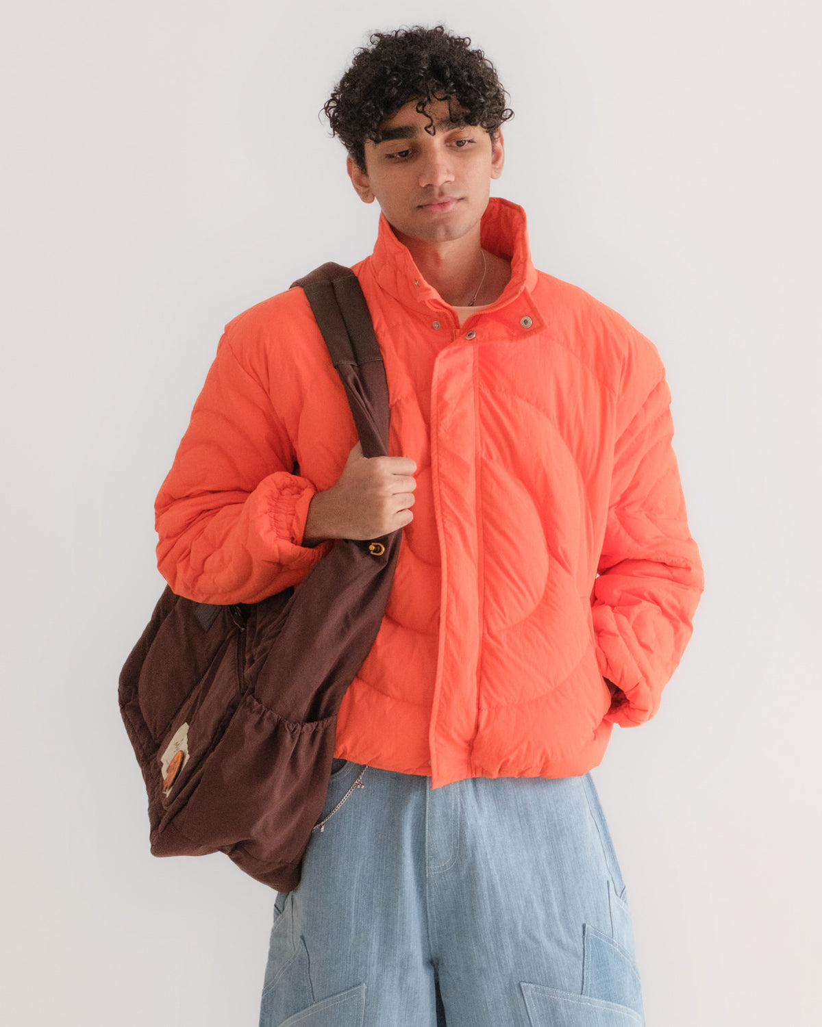 Man carrying the Gulabo Bag over the shoulder with the Jalebi Down Jacket and Khadi Katli Jorts