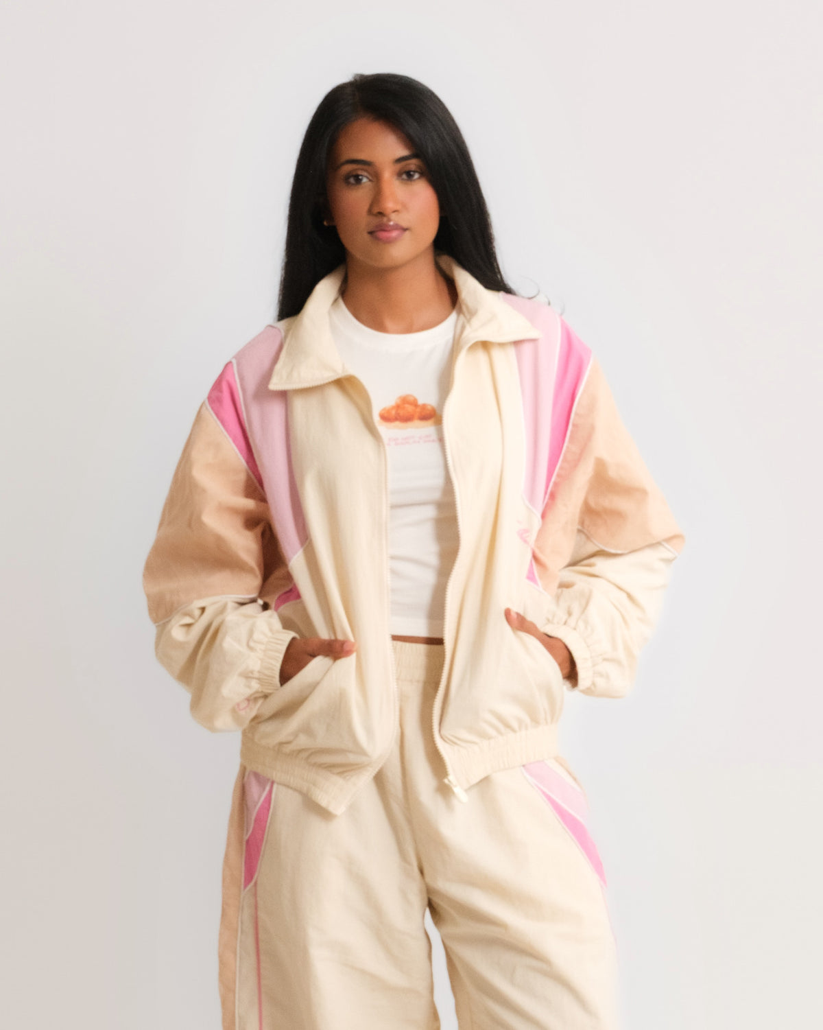 Woman wearing the Sweets Track Jacket in Rose Pink open over the Gulab Jamun Baby Tee, with the matching Track Pants #Color_Rose Pink