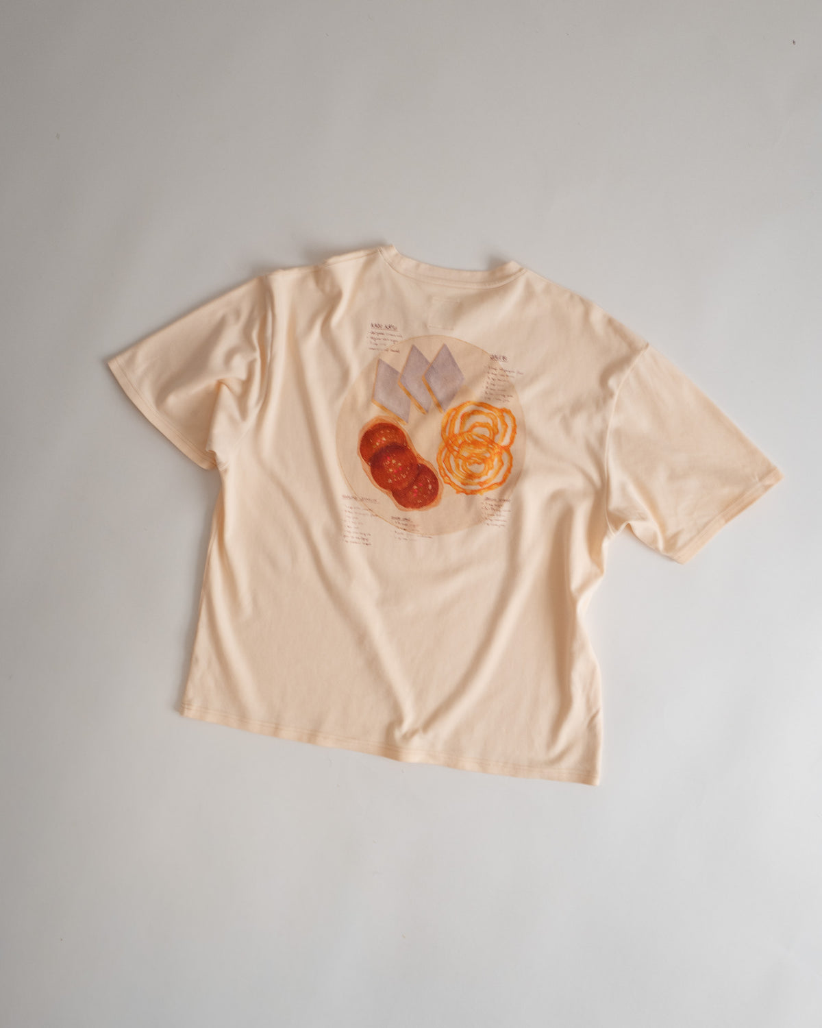 Recipe Tee flat lay from the back, watercolor sweets and their recipes printed across the back