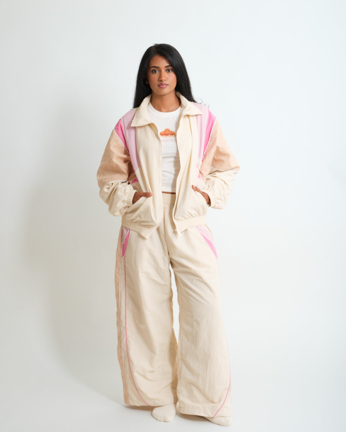Woman wearing the Sweets Track Jacket in Rose Pink open over the Gulab Jamun Baby Tee, with the matching Track Pants #Color_Rose Pink
